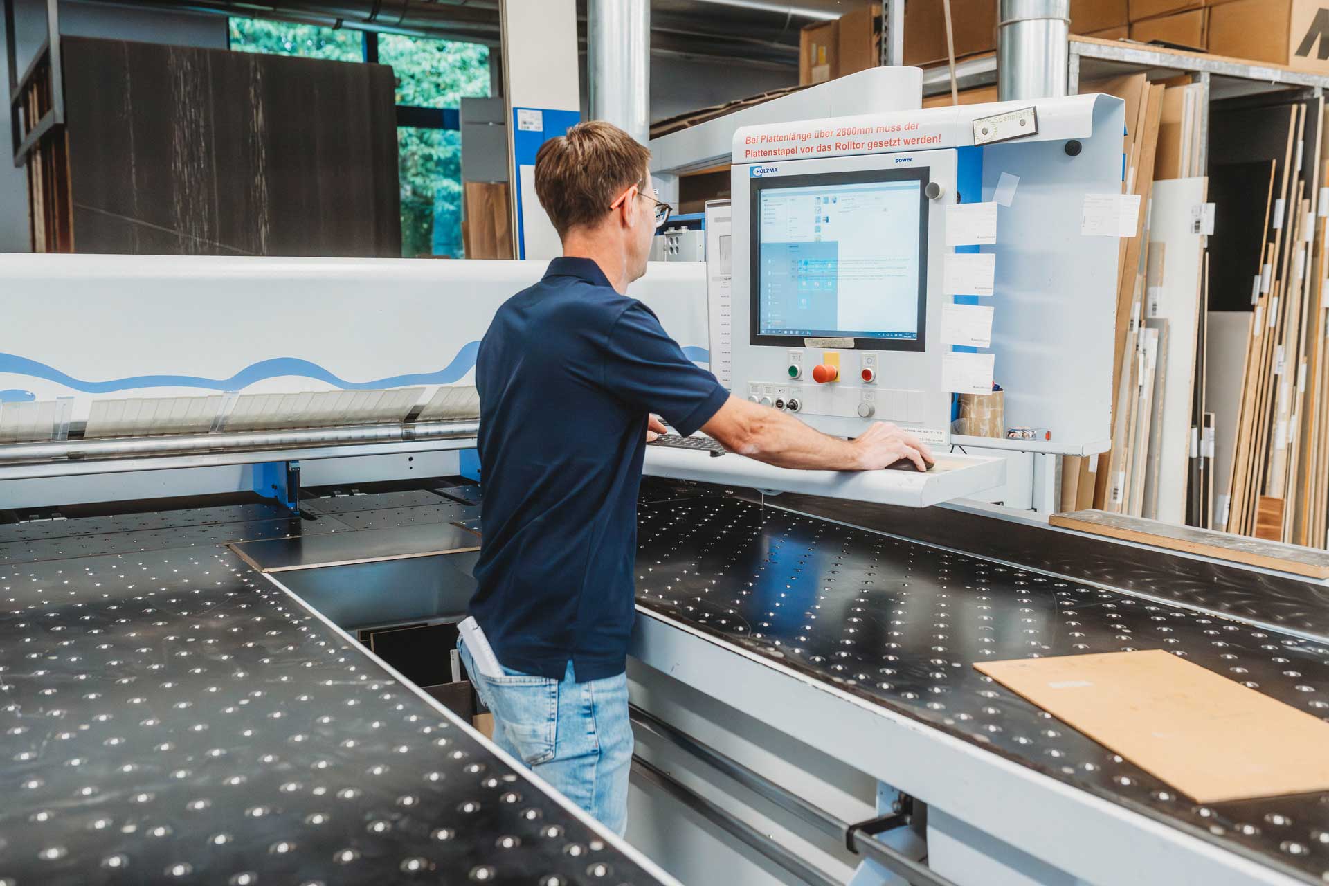 Detailaufnahme eines Handwerkers beim präzisen Zuschnitt von Holz in der Produktionshalle von Kampfmann Inneneinrichtungen﻿